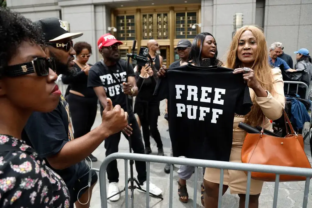 Aanhangers van Sean Combs houden voor de rechtbank een zwart shirt omhoog met de tekst Free Puff