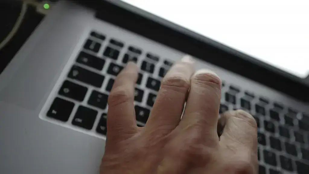 Een hand typt op een laptoptoetsenbord, van bovenaf gefotografeerd