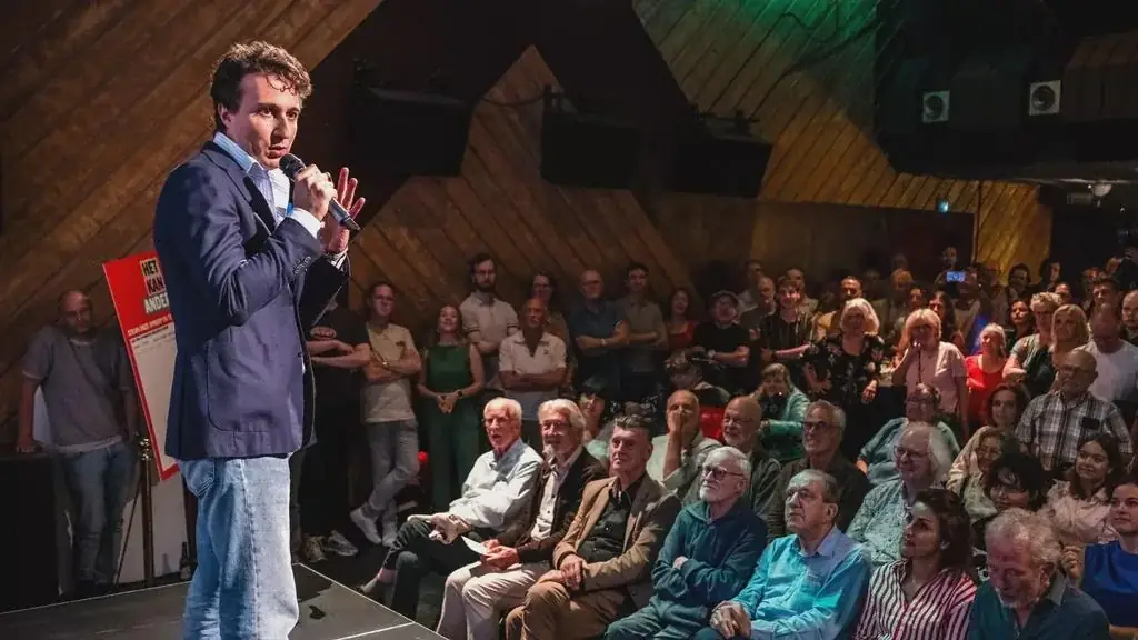 Jesse Klaver spreekt met een microfoon op het podium voor een volle zaal tijdens de ledenbijeenkomst in Utrecht