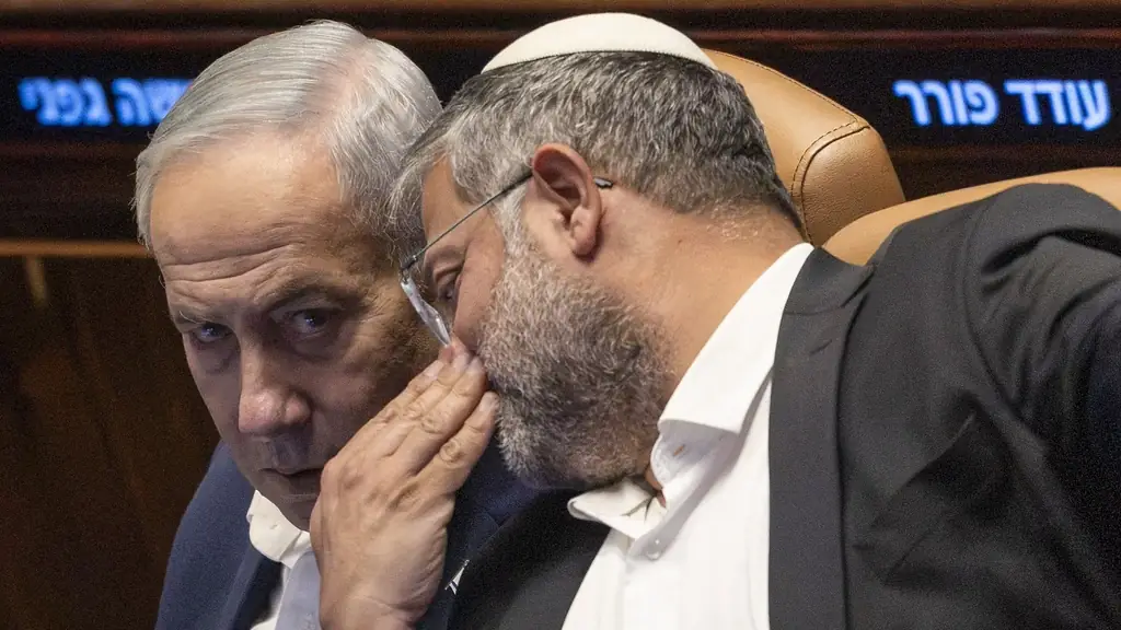 Ben-Gvir buigt zich naar Netanyahu om iets in zijn oor te zeggen tijdens een zitting in de Knesset