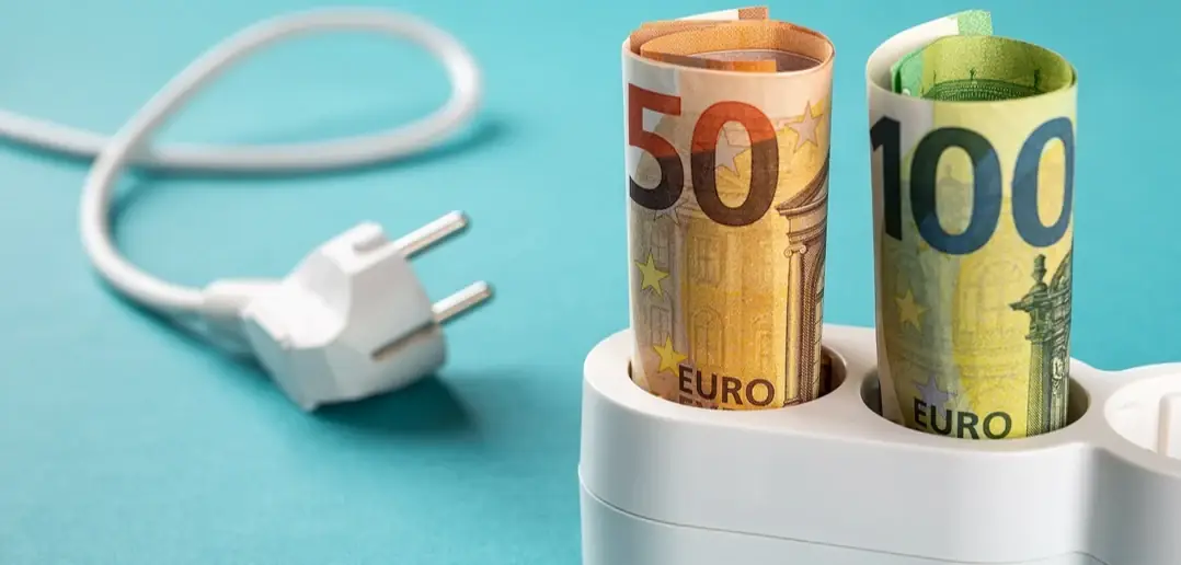 Twee opgerolde eurobiljetten van 50 en 100 euro steken als stekkers in een wit stekkerblok tegen een blauwe achtergrond