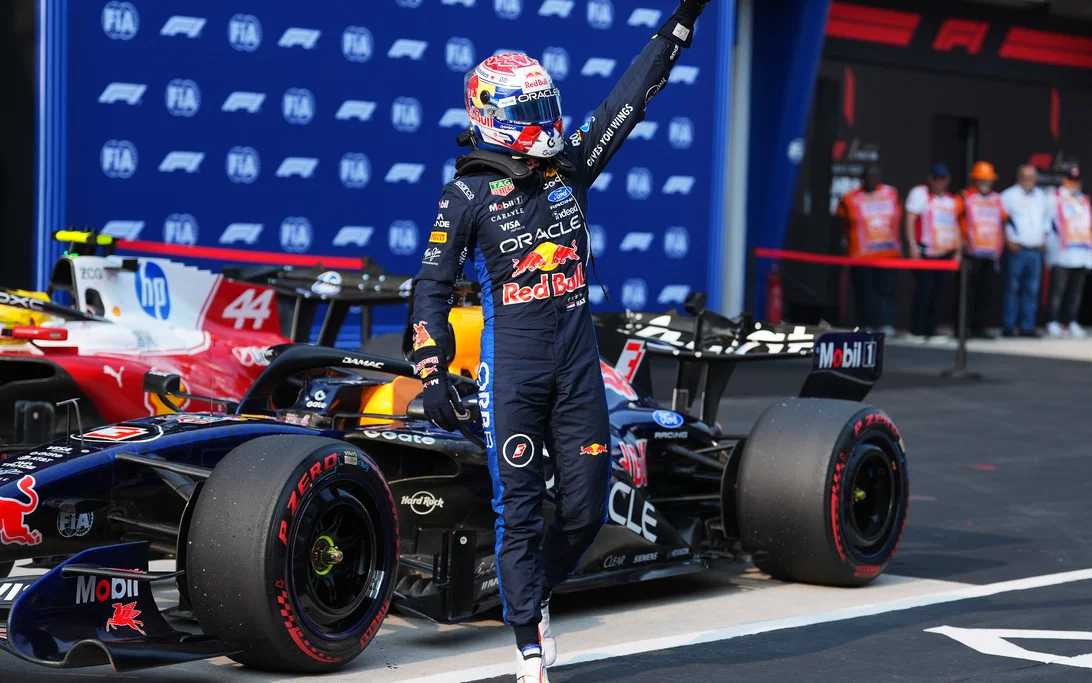 Max Verstappen steekt zijn arm omhoog naast zijn Red Bull in de pitstraat na zijn zege op Sepang