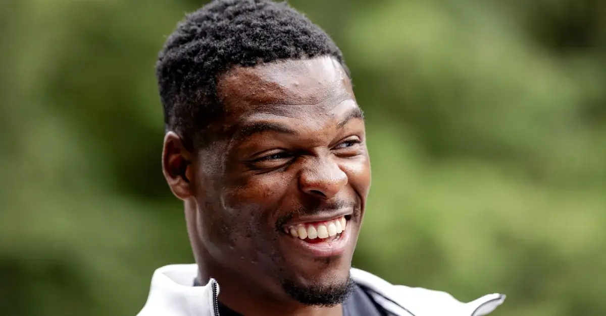 Denzel Dumfries lachend tijdens een persmoment, met groen op de achtergrond
