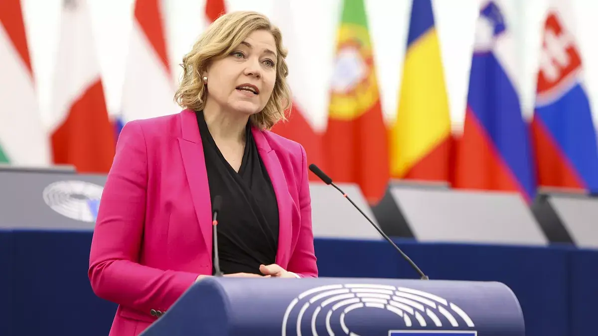 Eurocommissaris Henna Virkkunen in een roze blazer achter het spreekgestoelte van het Europees Parlement, met vlaggen van lidstaten achter haar