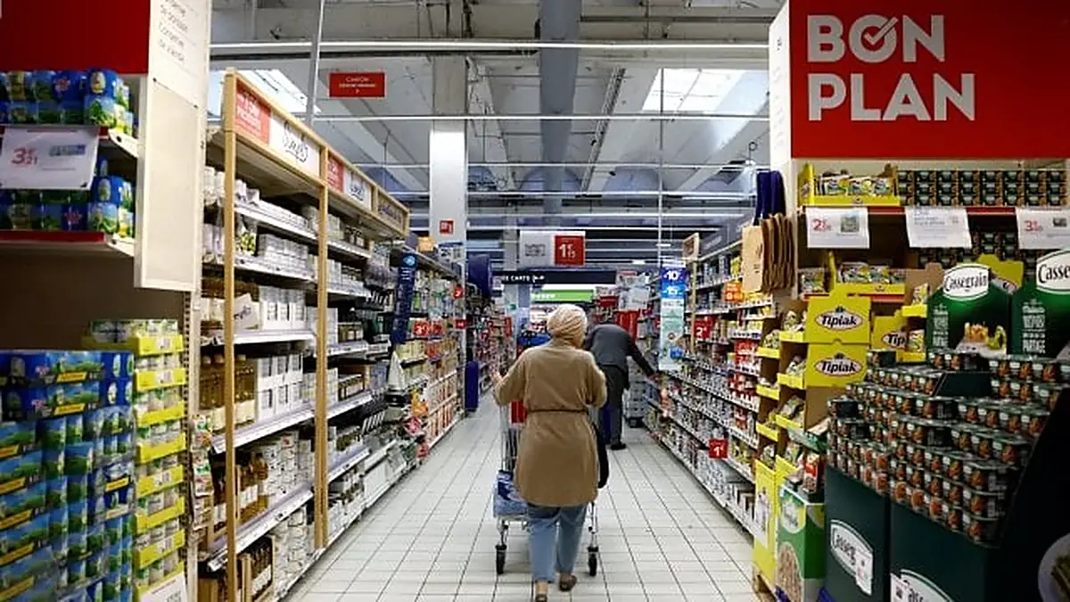 Gangpad in een Franse supermarkt met volle schappen en een groot bord met de tekst Bon Plan