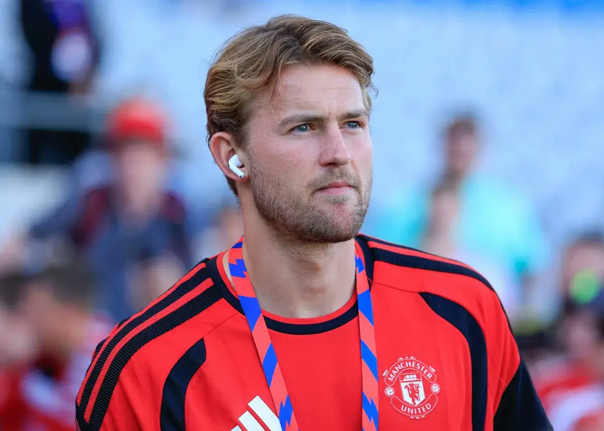 Matthijs de Ligt in een rood trainingsshirt van Manchester United kijkt langs de camera in een stadion