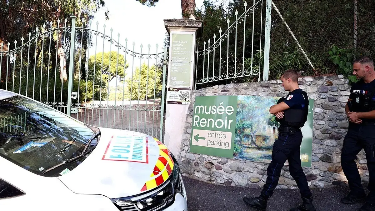 Twee Franse politieagenten bij het gesloten hek van het Renoir-museum, met een politieauto ervoor