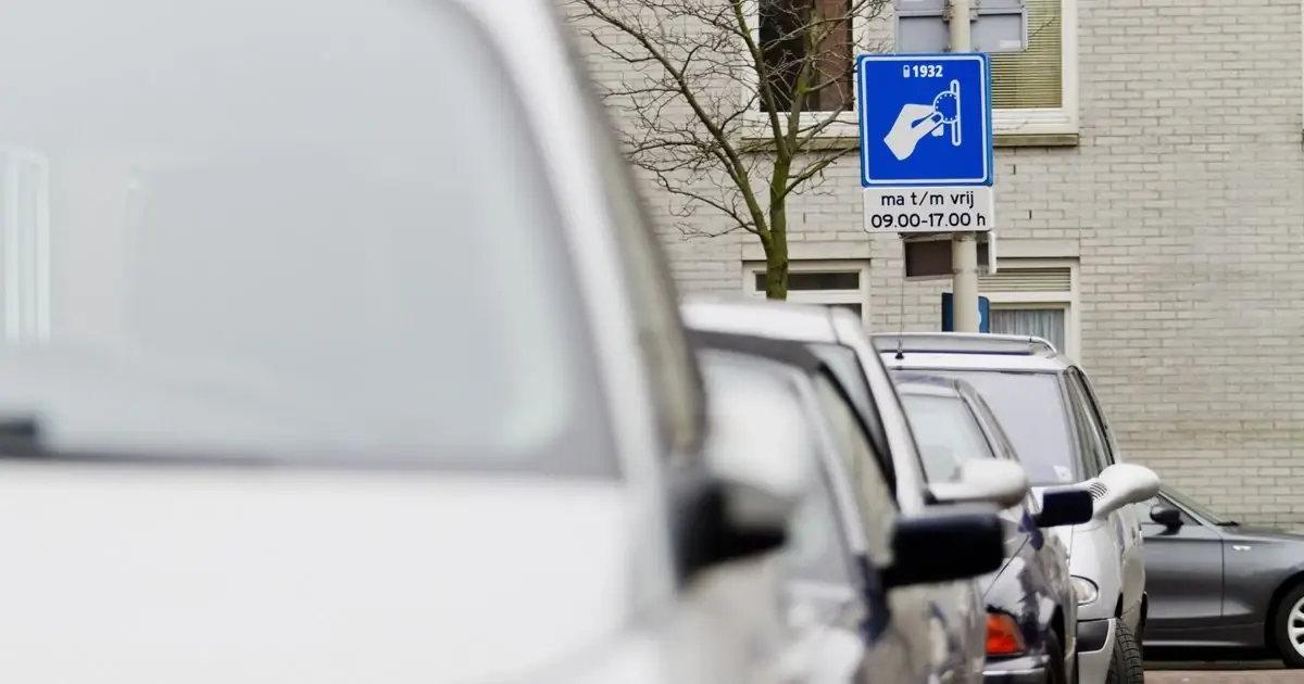 Een parkeerbord met betaalde uren naast een rij geparkeerde auto's in een woonwijk