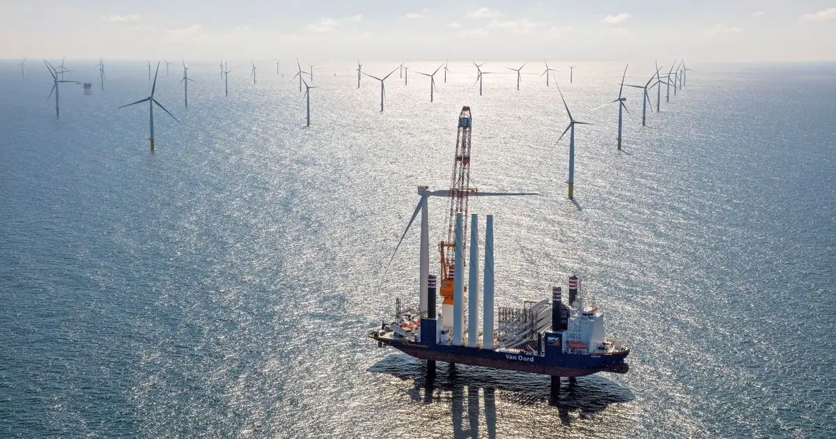 Luchtfoto van een windpark op de Noordzee met een installatieschip tussen de turbines