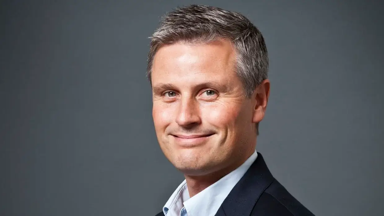 Portret van hoogleraar Claes de Vreese in pak, glimlachend tegen een grijze achtergrond