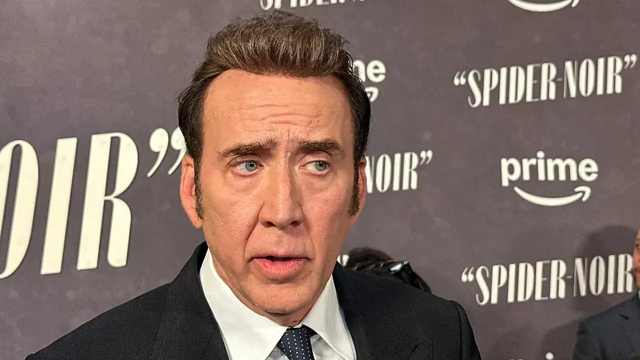 Nicolas Cage in donker pak met stropdas op een rode loper, voor een wand met de filmtitel Spider-Noir en het logo van Prime