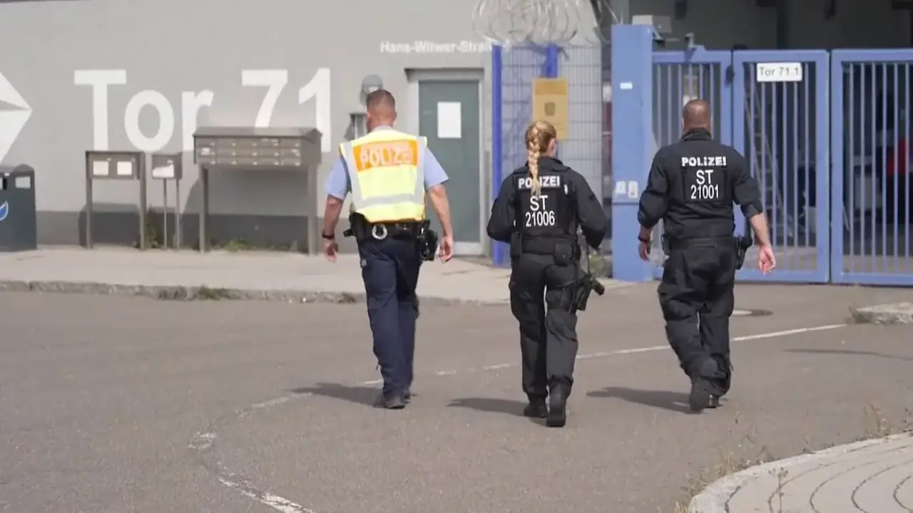 Drie Duitse politieagenten lopen over het asfalt naar poort Tor 71 van de luchthaven van Leipzig