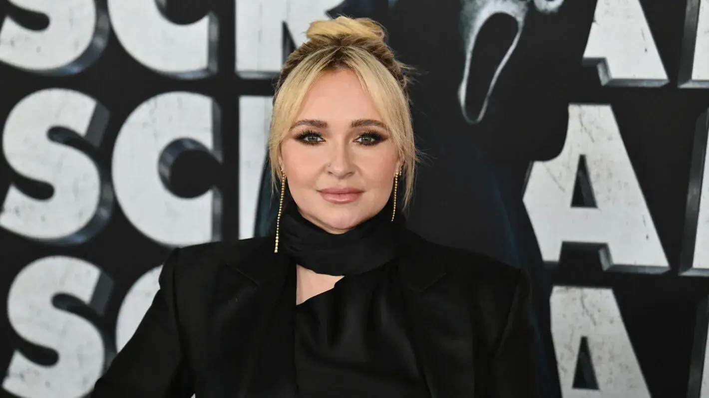 Hayden Panettiere in het zwart op de première van een Scream-film, met het logo van de film op de achtergrond