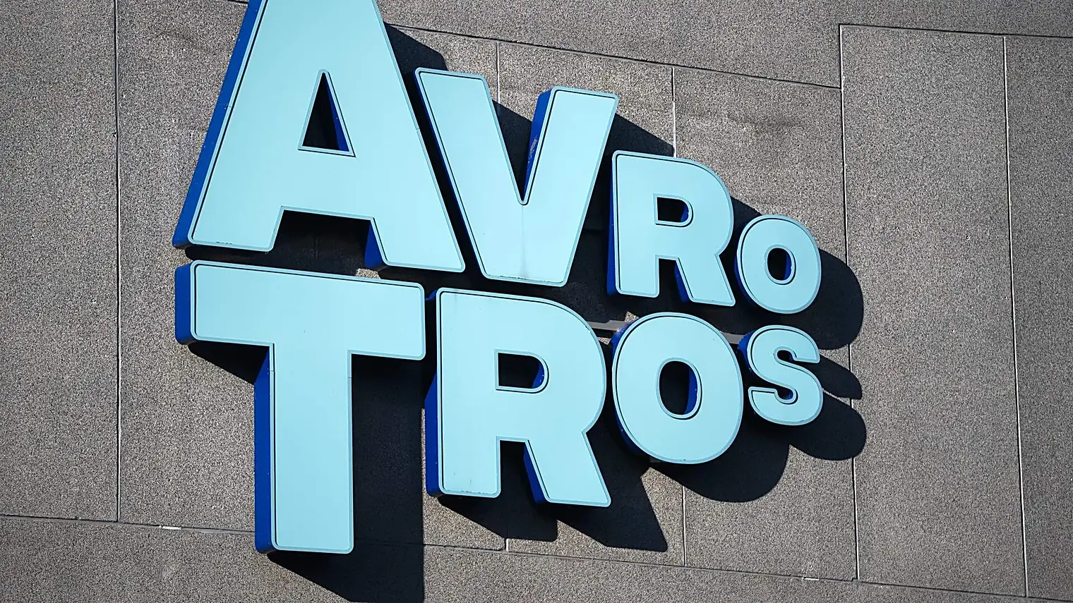 Het logo van AVROTROS in lichtblauwe letters op de grijze gevel van het omroepgebouw