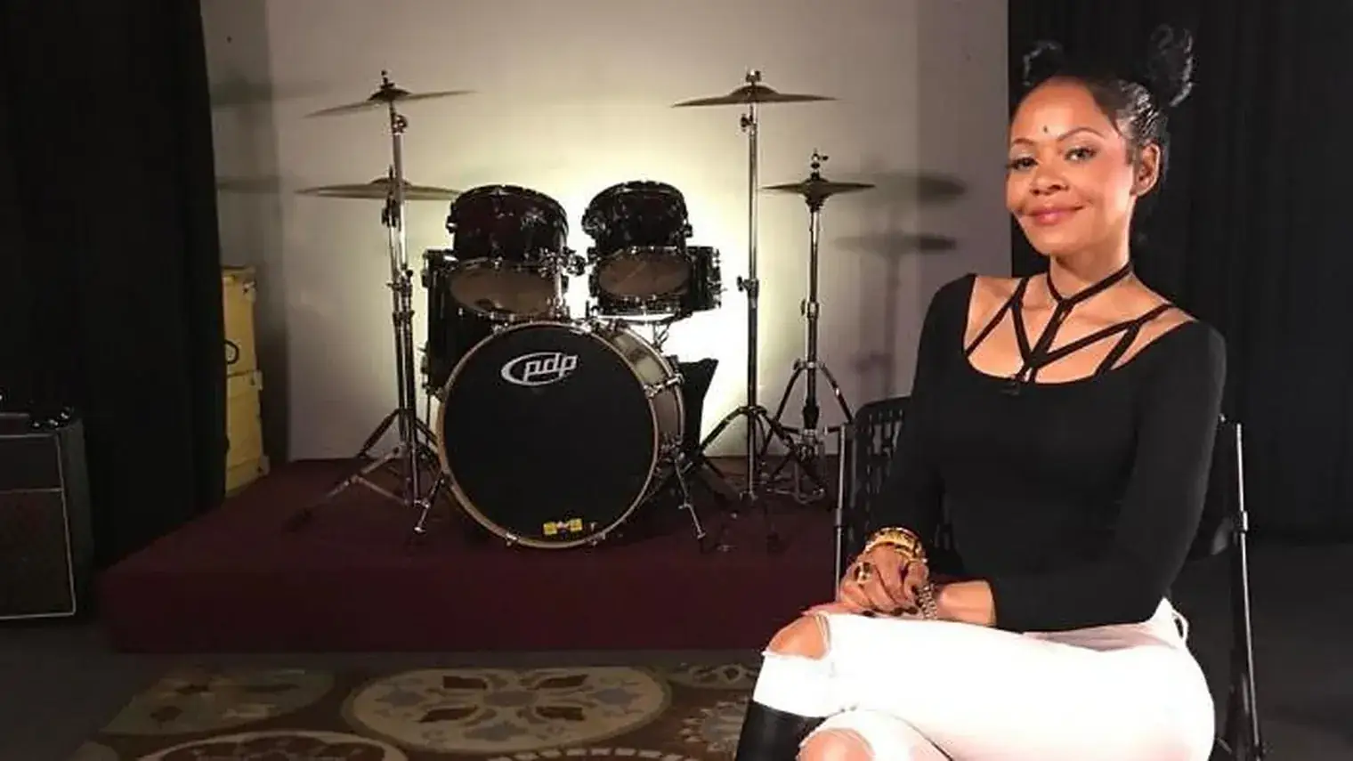 Carmen Bryan zittend tijdens een interview, met een drumstel op de achtergrond