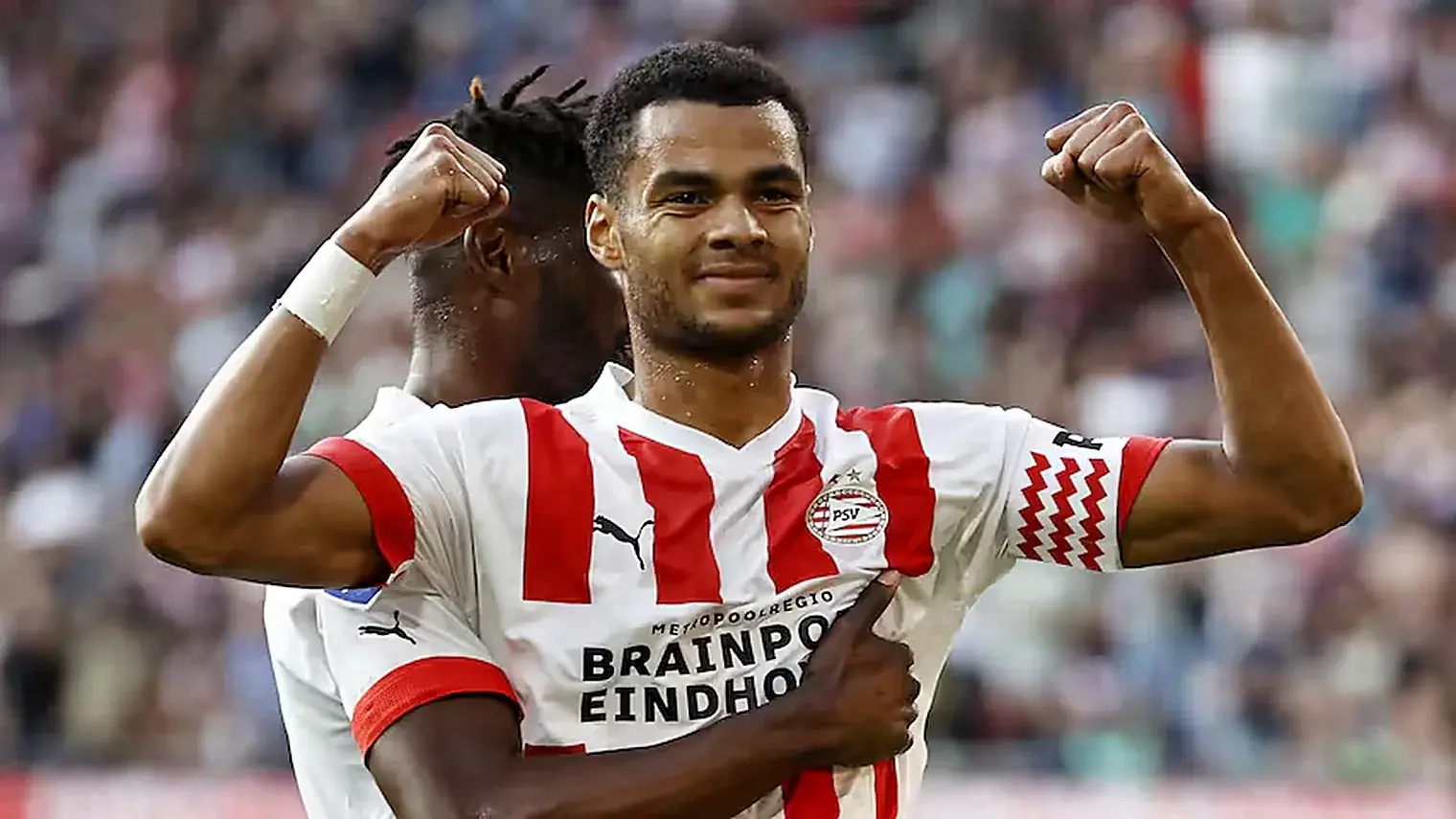 Cody Gakpo juicht met gebalde vuisten in het rood-witte shirt van PSV, met een ploeggenoot achter zich in het Philips Stadion