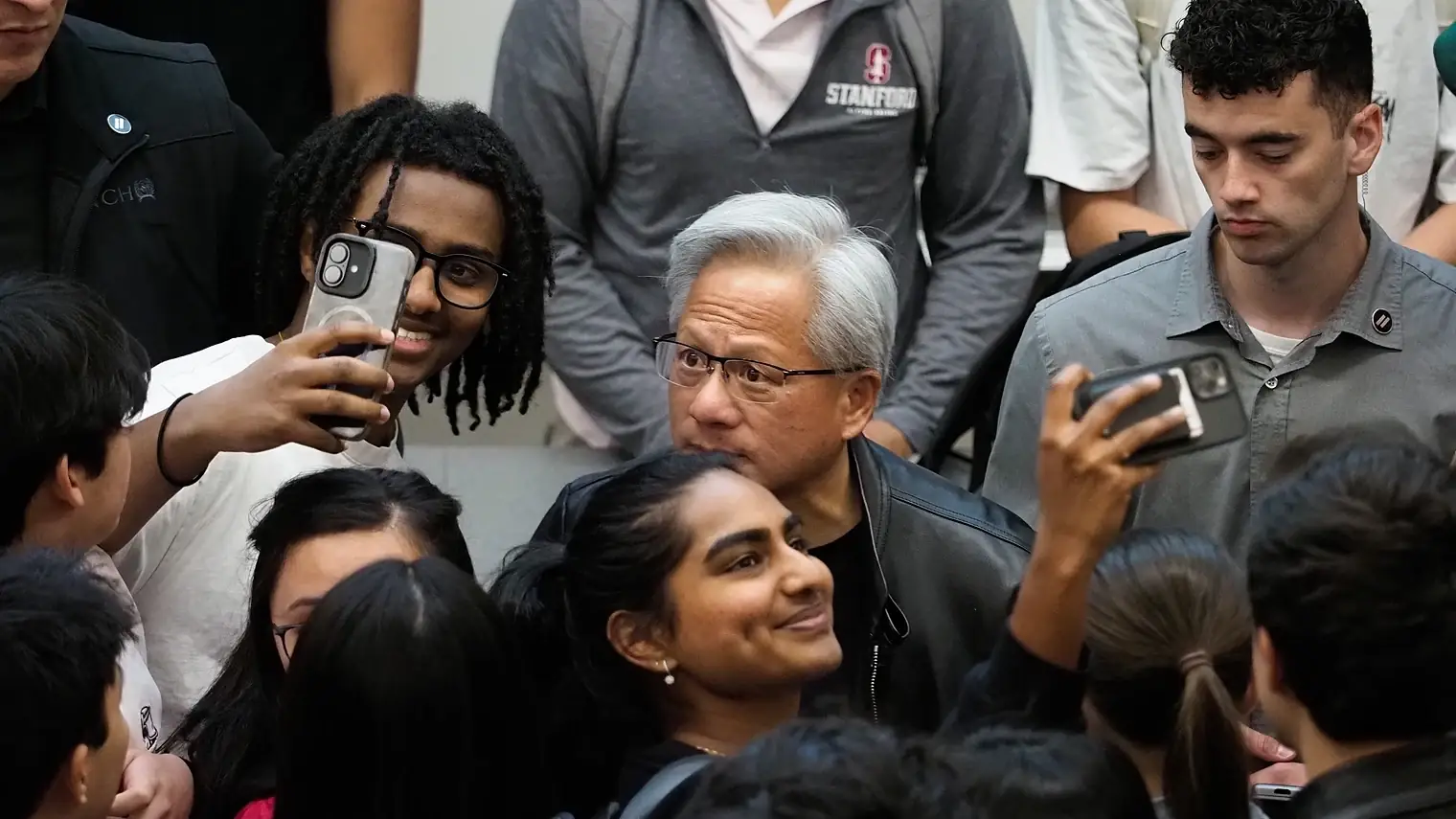 Jensen Huang staat omringd door studenten die hem met hun telefoons fotograferen