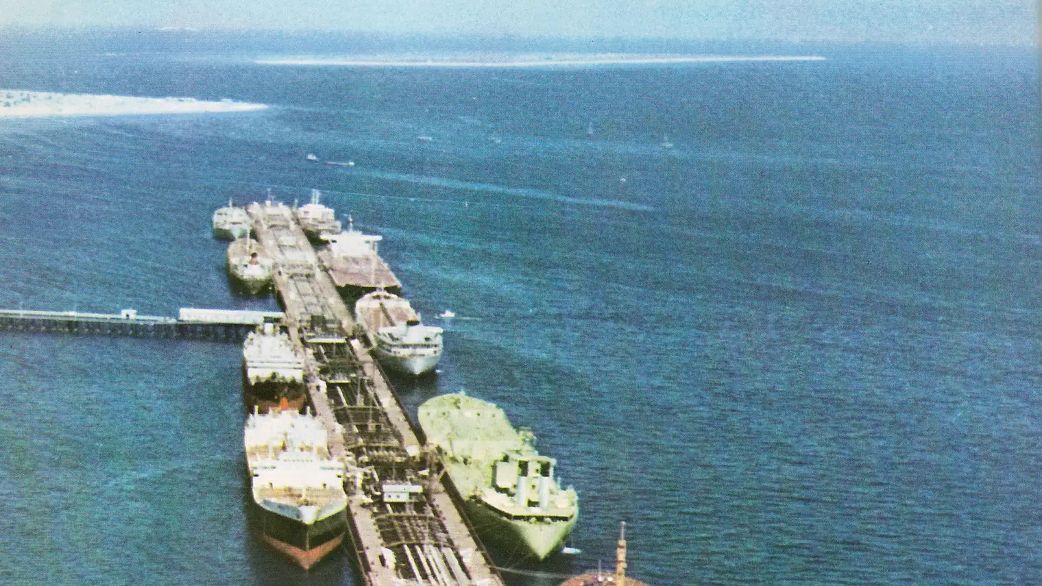 Luchtfoto van de olieterminal van Kharg-eiland, met meerdere olietankers afgemeerd aan een lange aanlegsteiger
