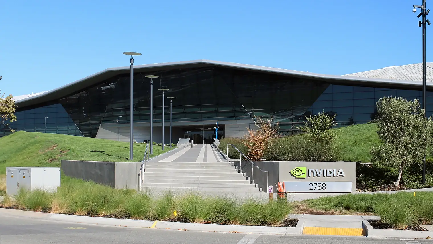 Het hoofdkantoor van Nvidia in Santa Clara, een laag gebouw met een driehoekig glazen dak en het Nvidia-logo bij de trap