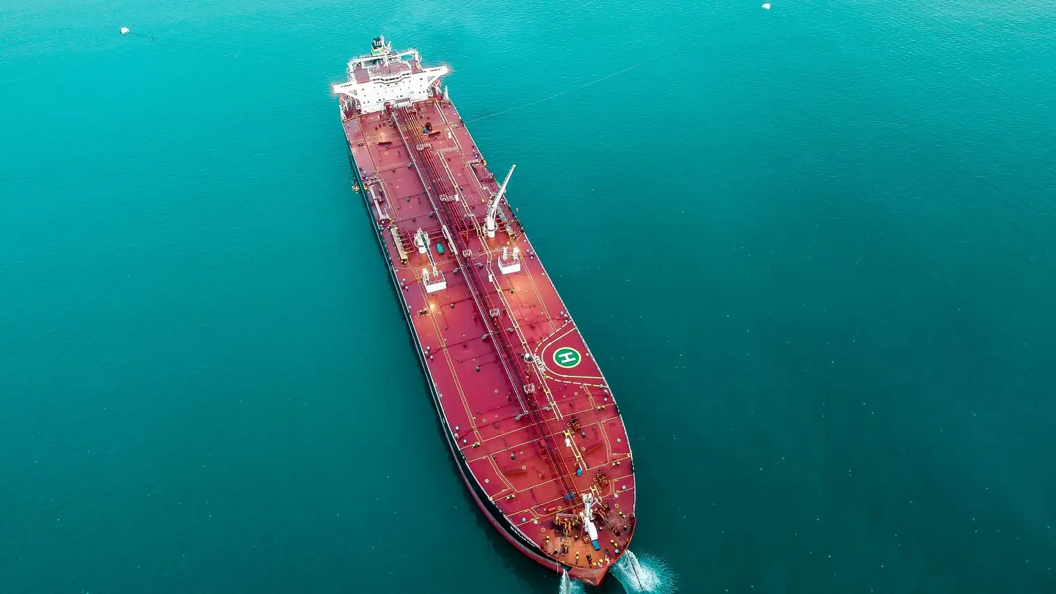 Luchtfoto van een grote olietanker die door turkoois water vaart