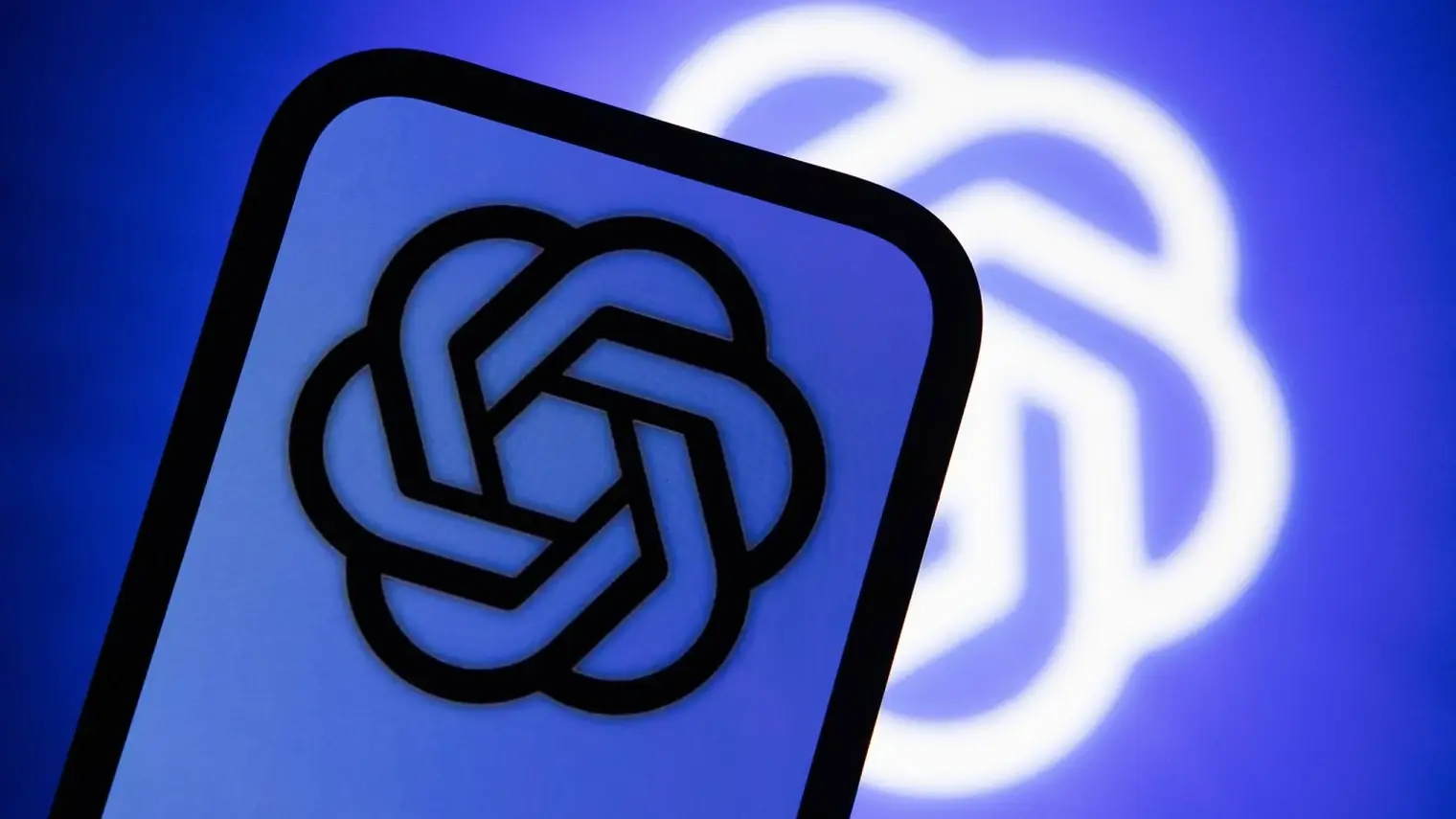 Een smartphone met het logo van OpenAI op het scherm, voor een blauwe achtergrond waarop hetzelfde logo groot is geprojecteerd