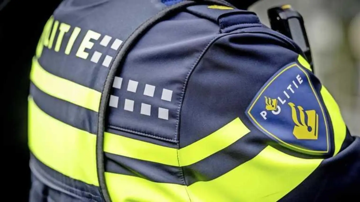 Close-up van het politie-embleem en de reflecterende strepen op de schouder van een Nederlands politie-uniform