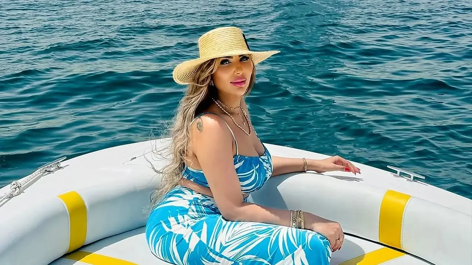 De Egyptische tv-presentatrice Sarah Khalifa met een strohoed op een boot, tegen de zee