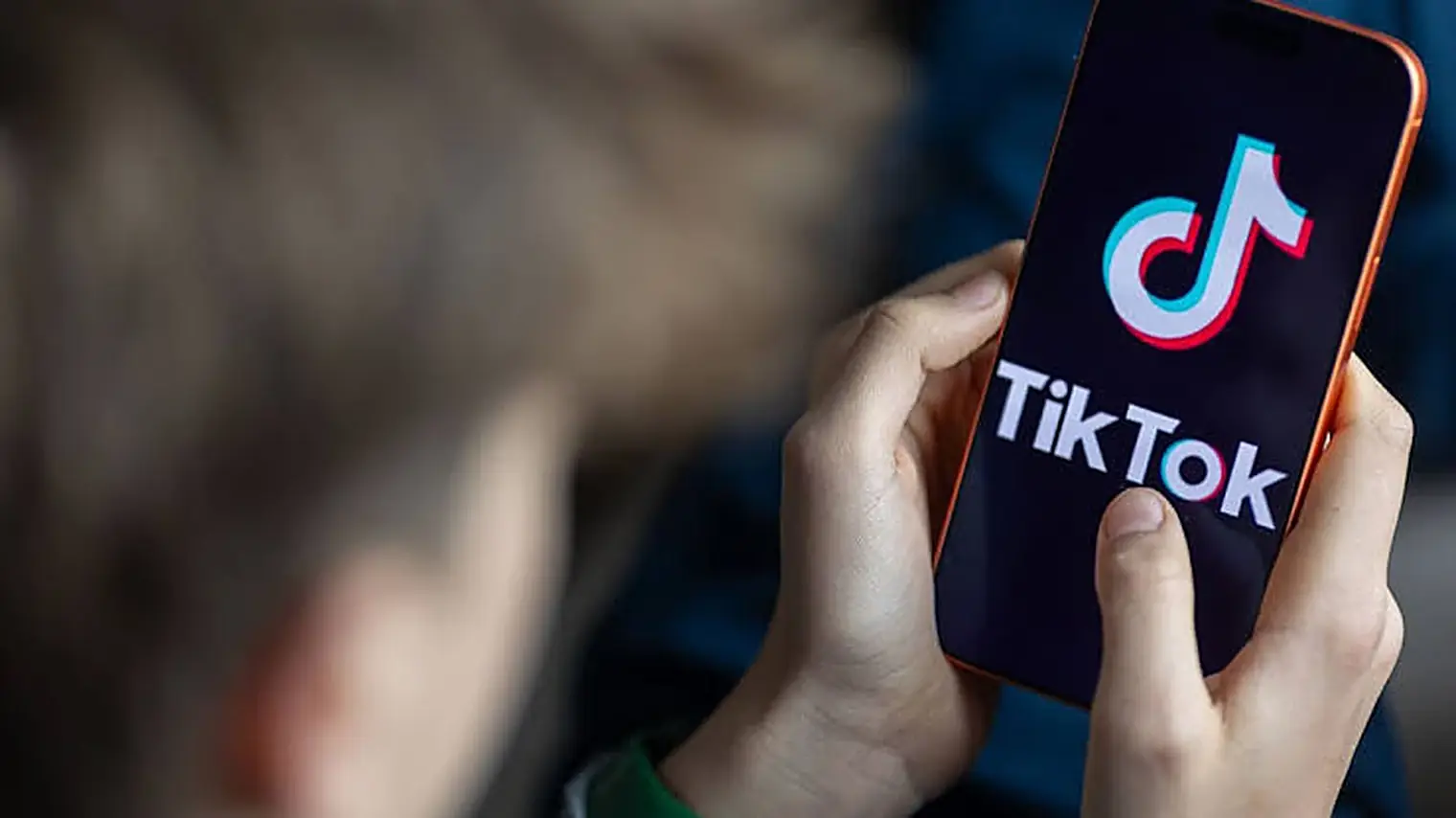 Over de schouder van een kind gefotografeerde telefoon met de TikTok-app open