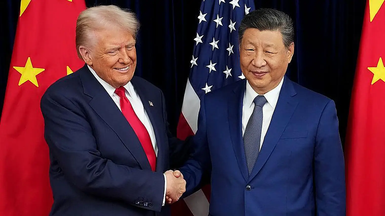 President Trump en president Xi Jinping geven elkaar een hand voor de Chinese en Amerikaanse vlag, beiden in donkerblauw pak