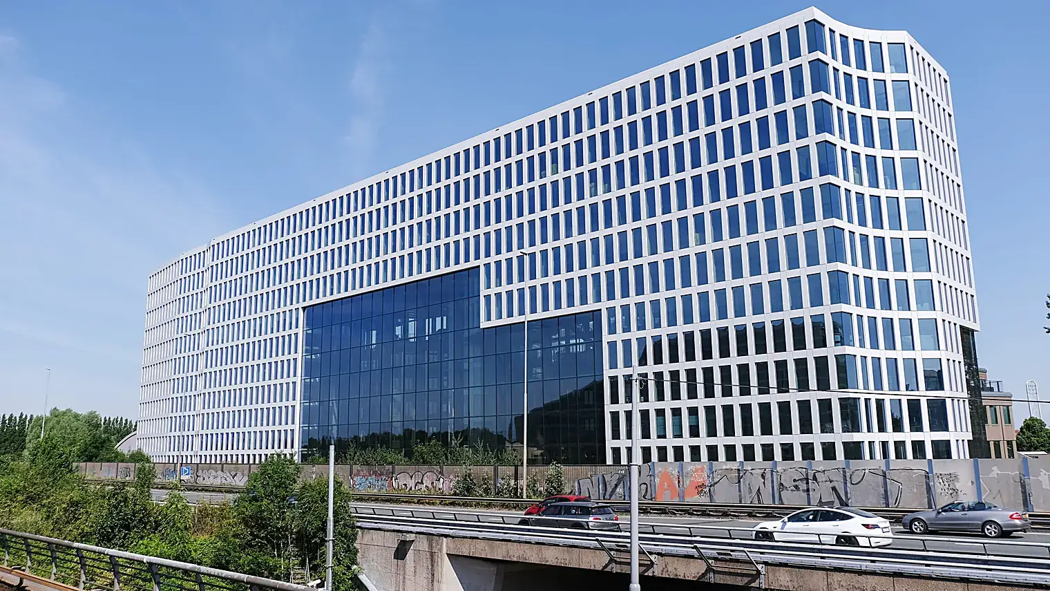 Het witte kantoorgebouw met blauwe glasgevels waar Uber zijn Europese hoofdkantoor heeft, gezien vanaf de snelweg langs Amsterdam