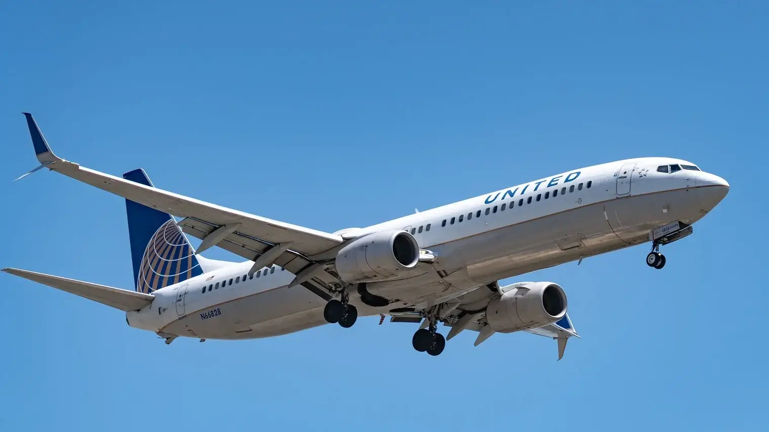 Een Boeing 737 van United Airlines in de lucht tegen een strakblauwe hemel, met het landingsgestel nog uit