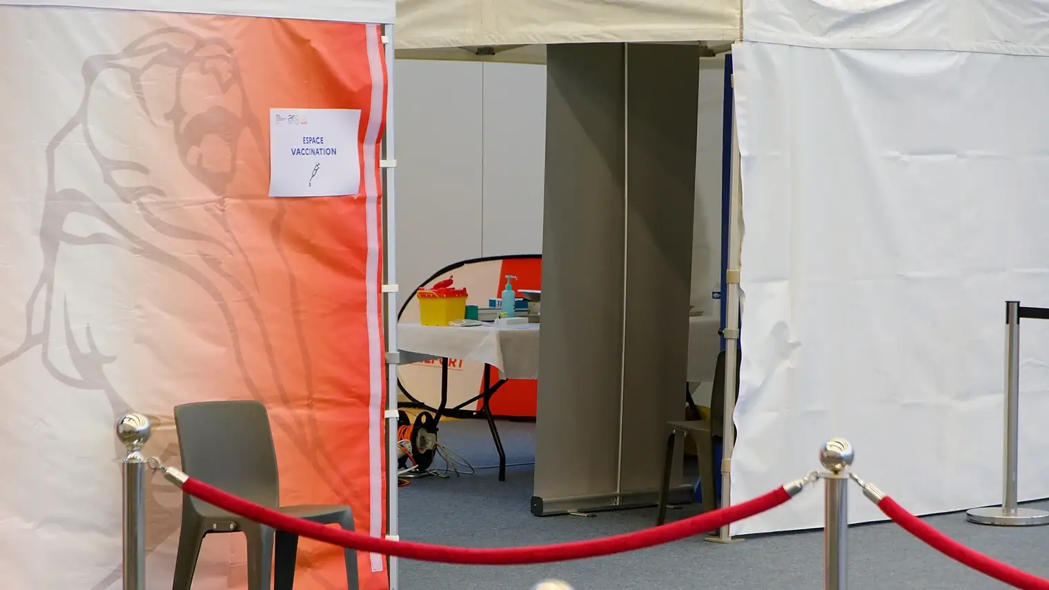 Lege vaccinatiepost in een tent met een bordje ESPACE VACCINATION, afgezet met een rood koord
