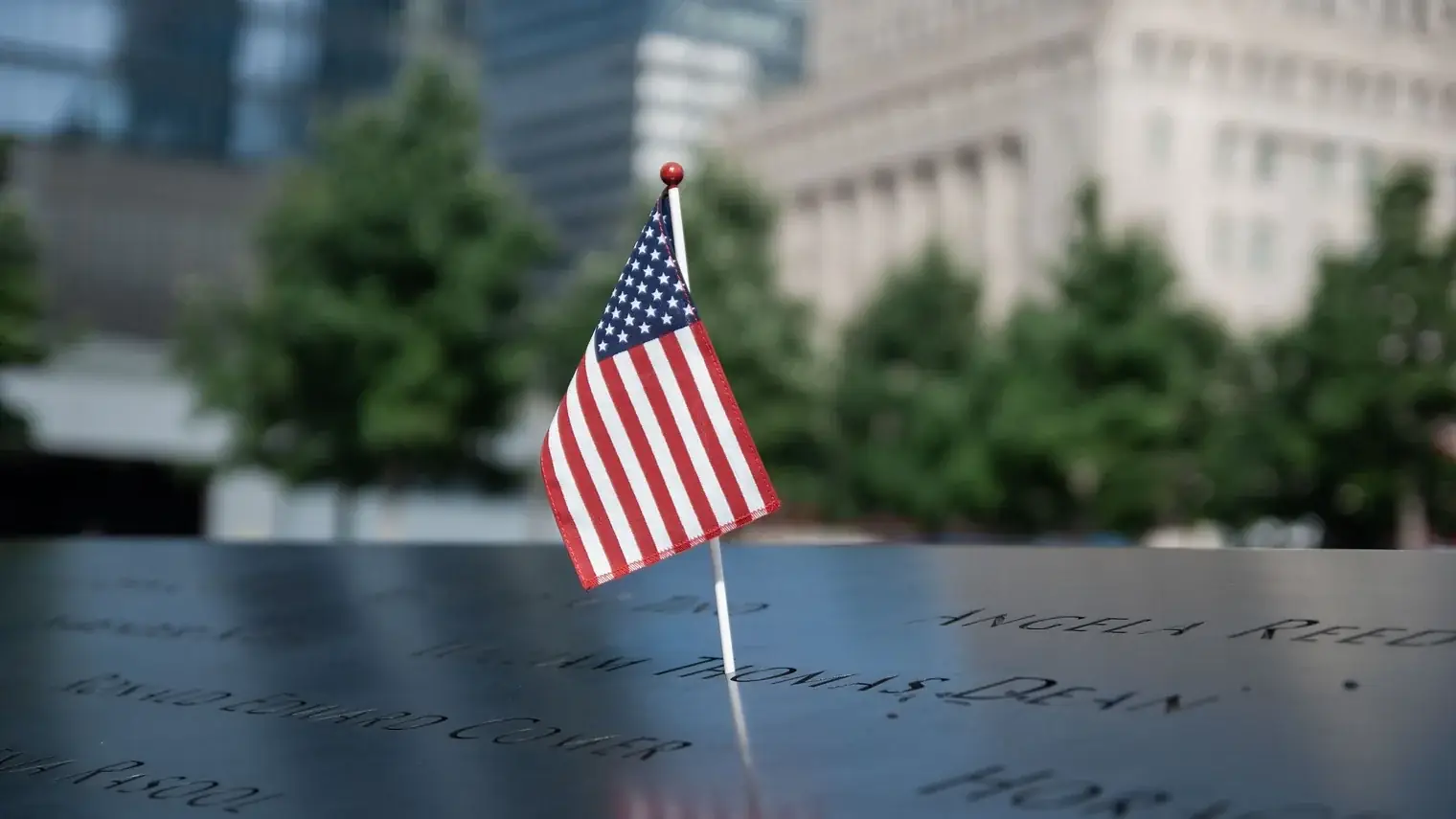 Een kleine Amerikaanse vlag op de rand van het 9/11-monument in New York, met de namen van slachtoffers gegraveerd in het brons