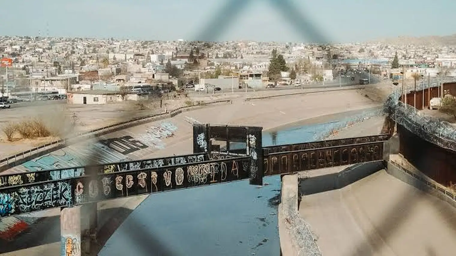 Uitzicht door een prikkeldraadhek op de grens tussen de Verenigde Staten en Mexico, met de stad Ciudad Juárez op de achtergrond