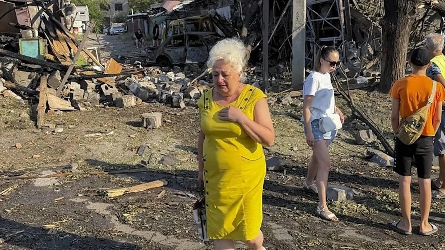 Bewoners lopen langs verwoeste huizen en een uitgebrand busje tussen puin en omgevallen bomen