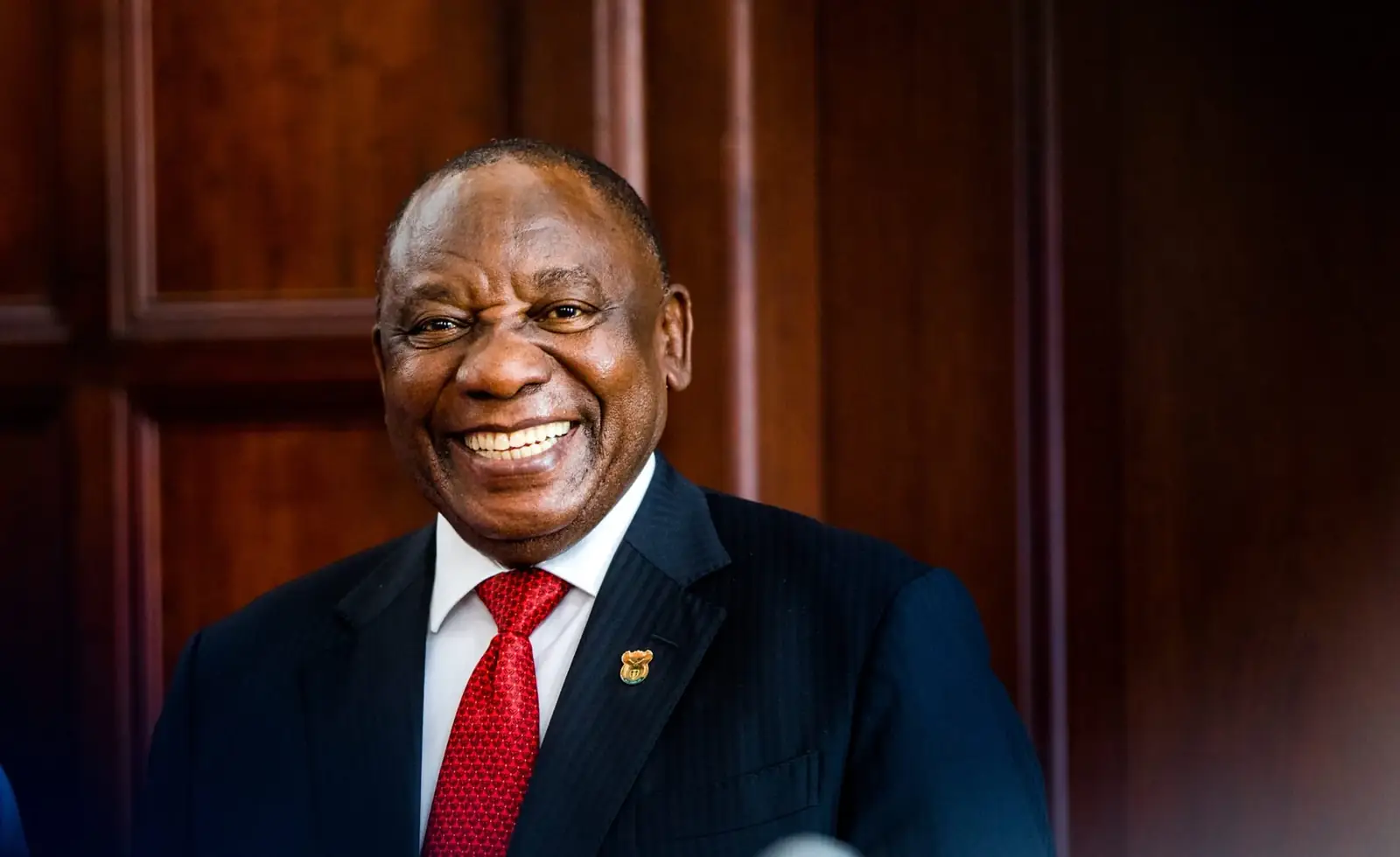 Cyril Ramaphosa, president van Zuid-Afrika, lachend in pak met rode stropdas