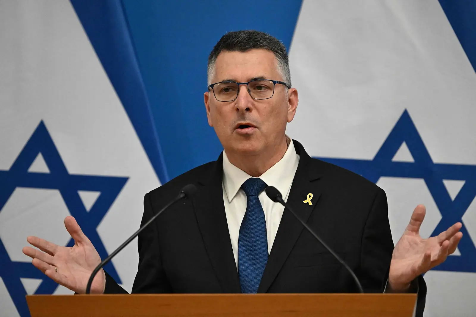 De Israelische minister van Buitenlandse Zaken Gideon Saar achter een katheder, voor twee vlaggen