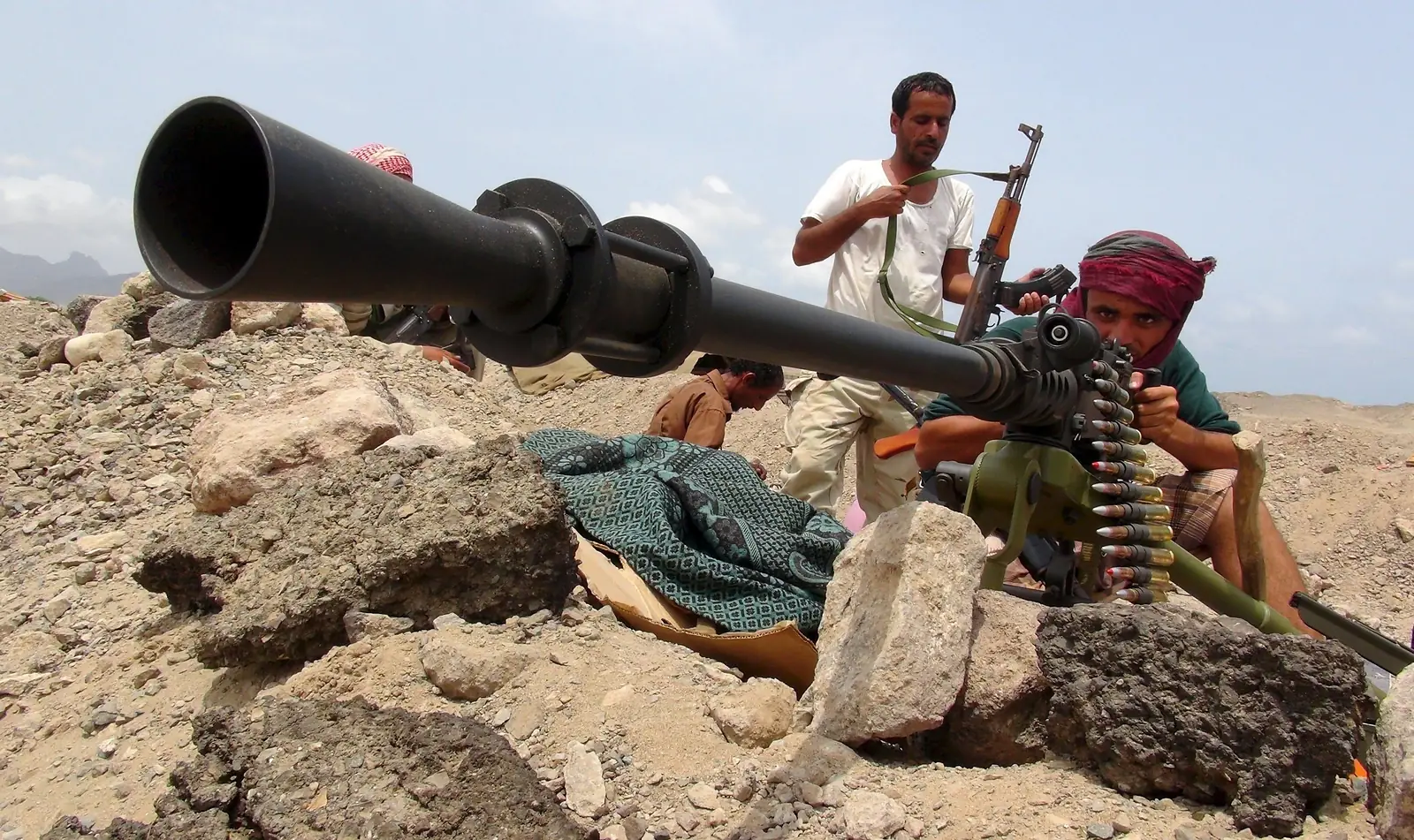 Houthi-strijders bemannen een zware mitrailleurstelling tussen rotsblokken in Jemen