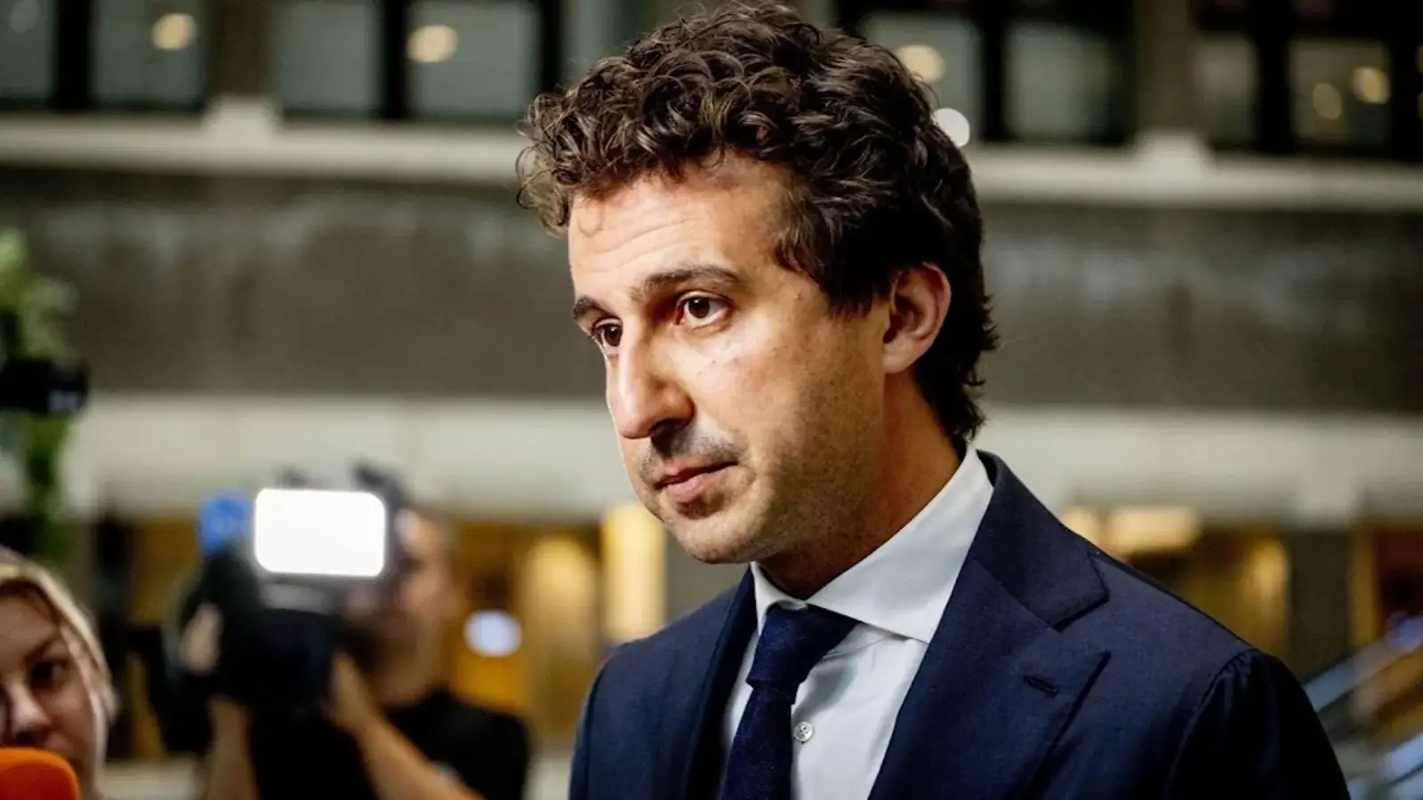 Jesse Klaver loopt langs camera's in de Tweede Kamer, op de achtergrond een fotograaf