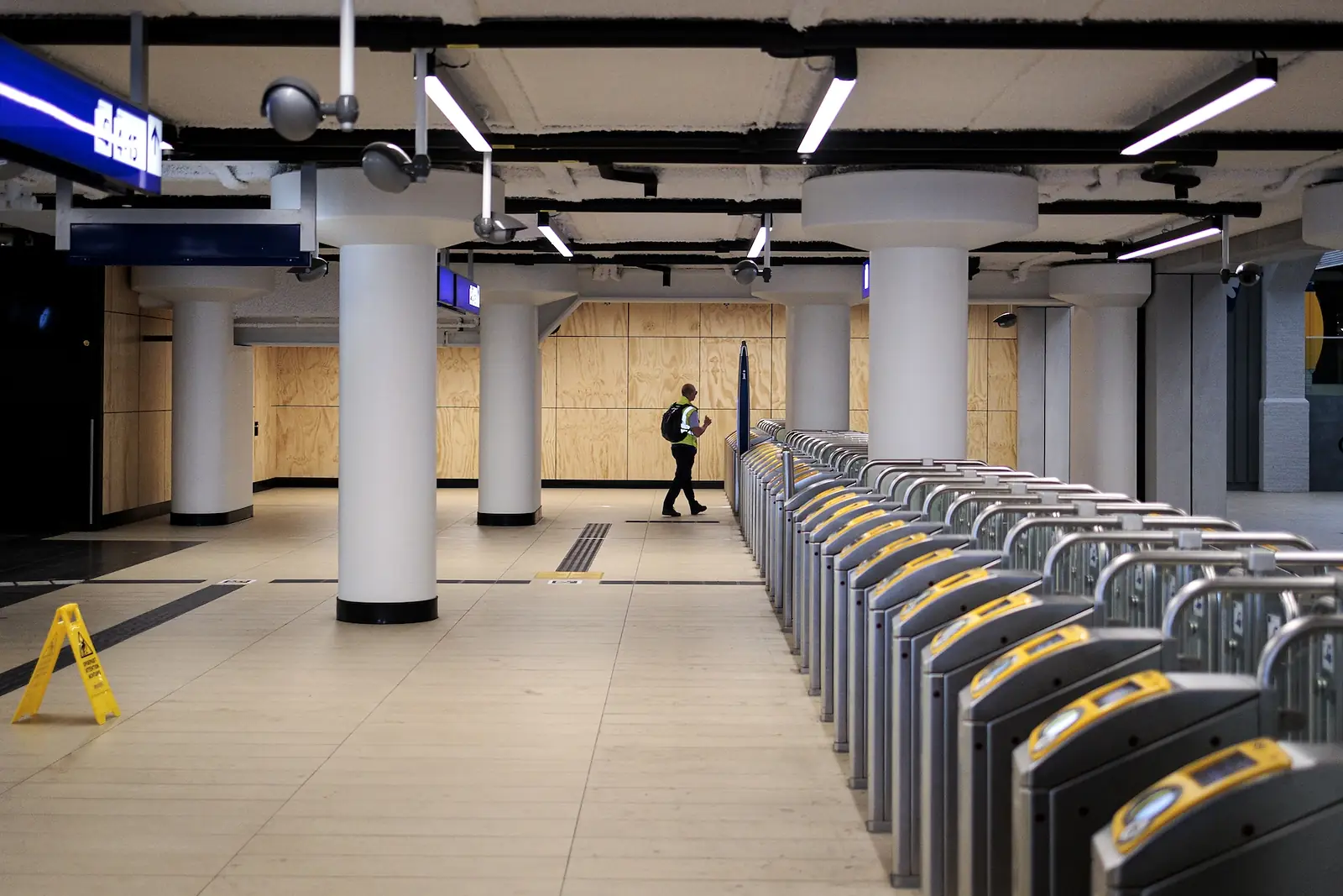Lege incheckpoortjes en een verlaten stationshal, met op de achtergrond één persoon die alleen over het perron loopt
