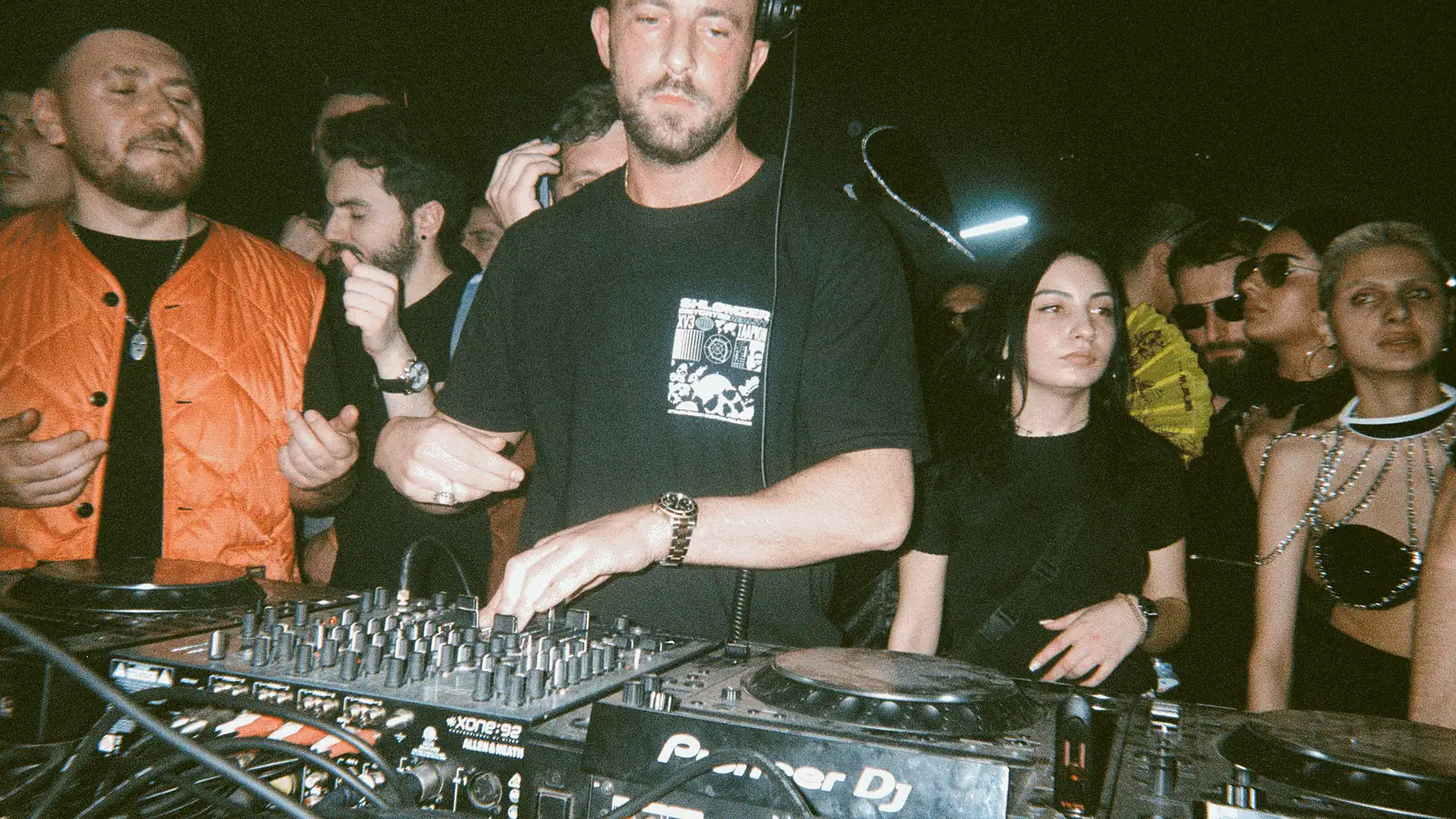 Shlømo draait plaat achter de draaitafels tijdens een Boiler Room-set, met publiek eromheen