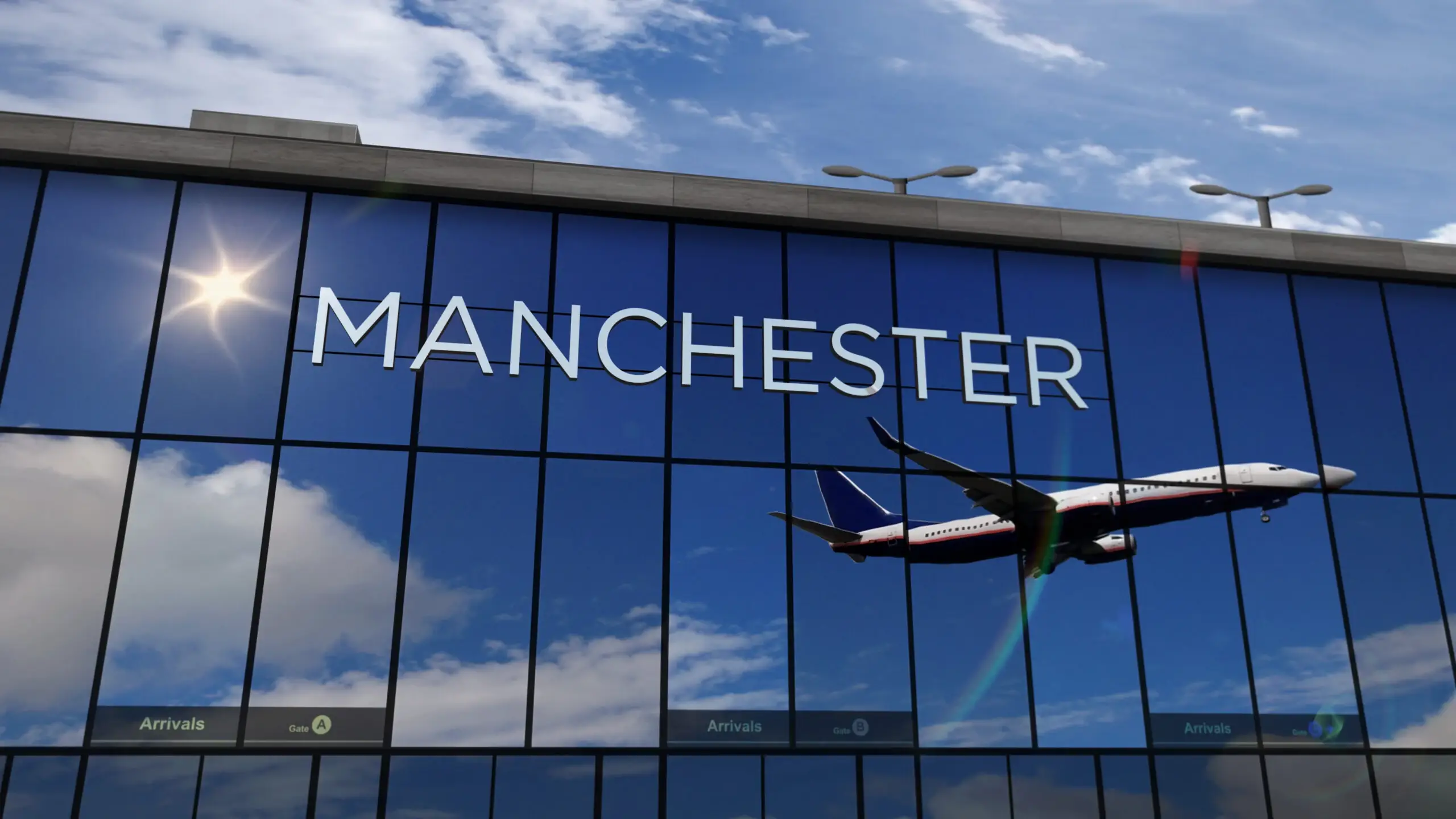 Glasgevel van de terminal van Manchester Airport met de naam in grote letters, met daarin een landend vliegtuig weerspiegeld