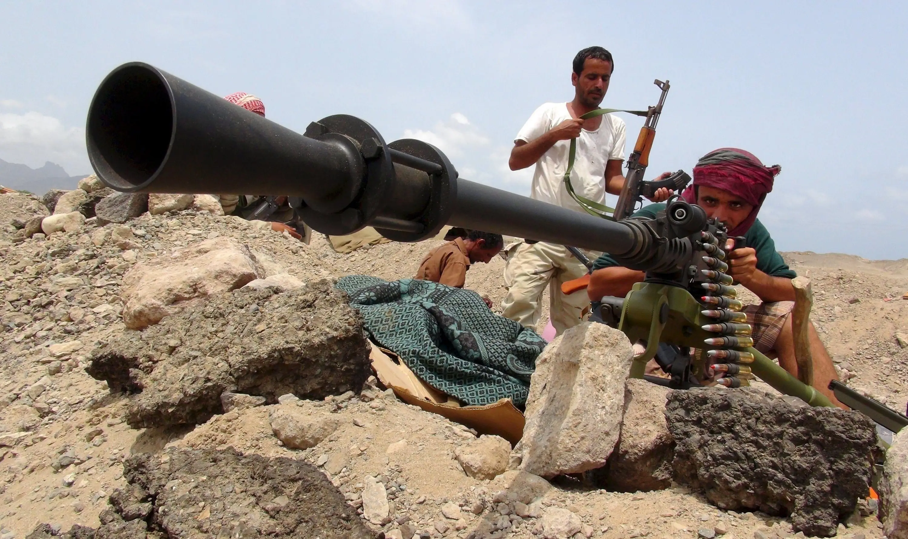 Houthi-strijders bemannen een zware mitrailleurstelling tussen rotsblokken in Jemen