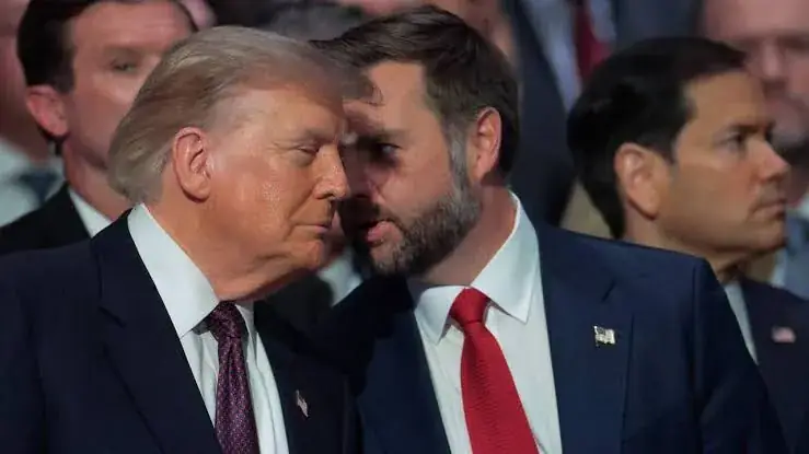 Donald Trump overlegt fluisterend met vicepresident JD Vance, met minister Marco Rubio op de achtergrond tussen andere aanwezigen