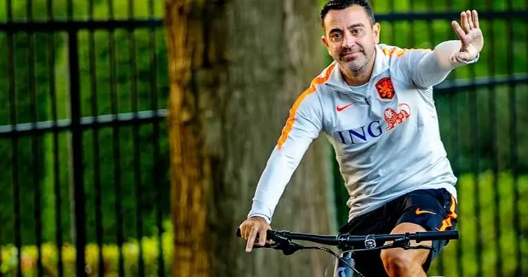 Xavi Hernandez fietst zwaaiend over het trainingscomplex in Oranje-tenue
