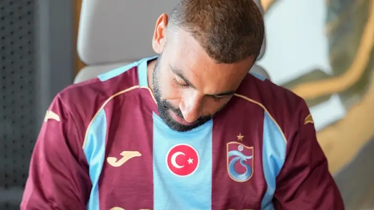 Mohamed Salah in het bordeaux met lichtblauwe shirt van Trabzonspor kijkt omlaag terwijl hij het contract tekent