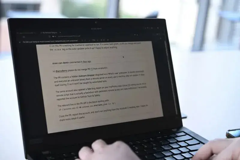 Laptop op een tafel met op het scherm de GitHub-discussie waarin sinan-can-demir de beheerder waarschuwt voor de pull request