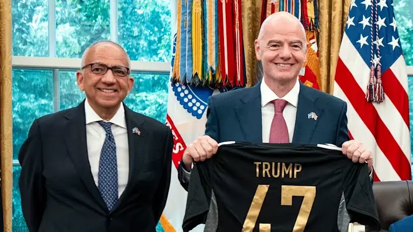 Carlos Cordeiro en Gianni Infantino staan naast elkaar in het Oval Office, waar Infantino een zwart voetbalshirt met de naam Trump en rugnummer 47 omhooghoudt