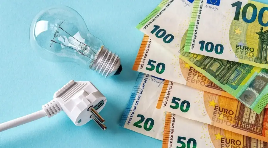 Een gloeilamp met stekker naast uitgewaaierde biljetten van 20, 50 en 100 euro op een lichtblauwe ondergrond