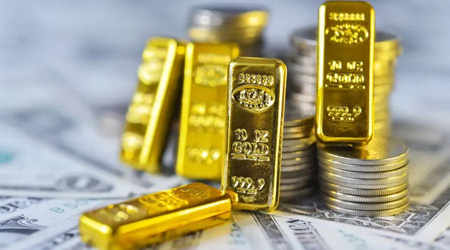 Goudbaren van tien ounce en stapels munten liggen op Amerikaanse dollarbiljetten